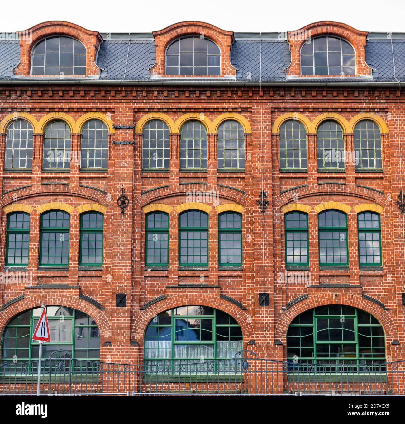 red brick facade of old industrial building with large glass windows Stock Photo