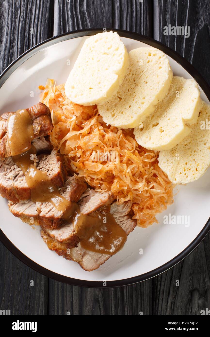 Roasted Pork, Dumplings and Sauerkraut Vepro knedlo zelo close-up in a plate on the table. Vertical top view from above Stock Photo