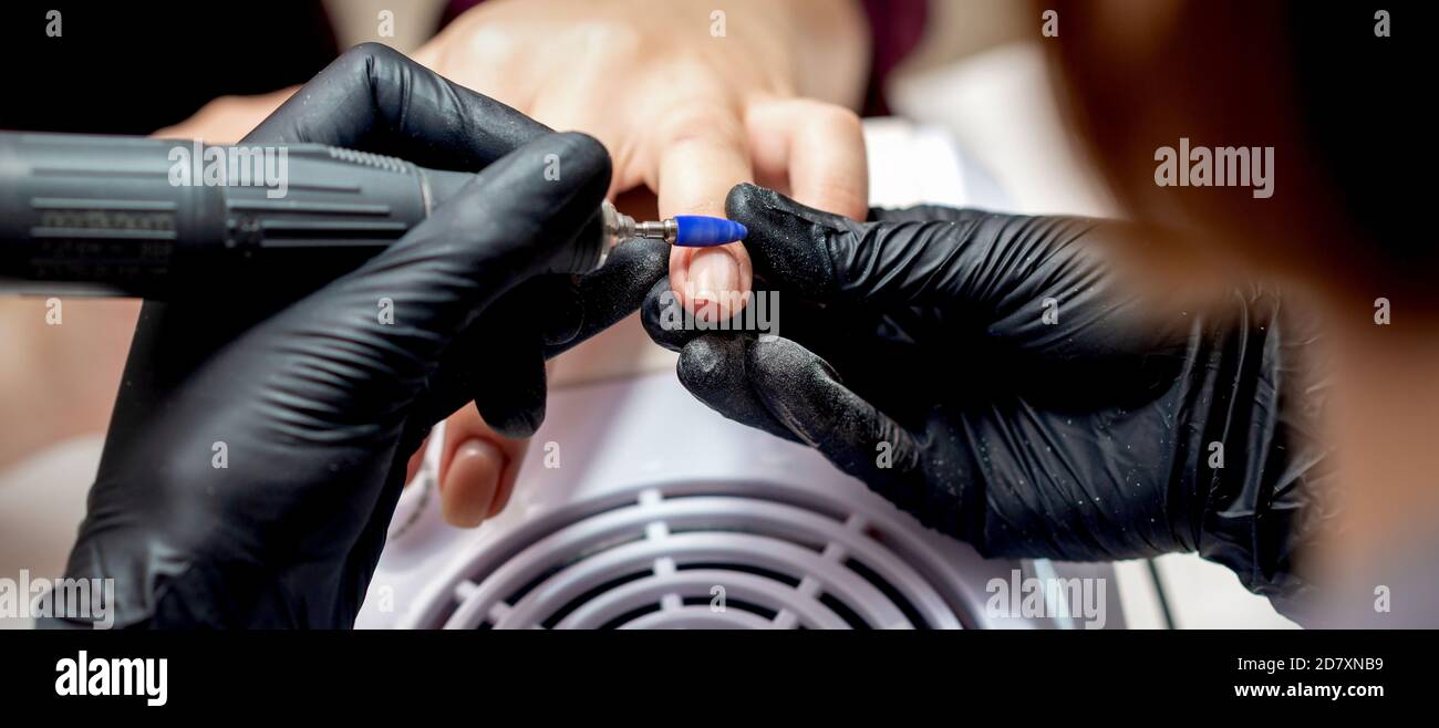 Manicure master applying electric nail file drill to fingernails of