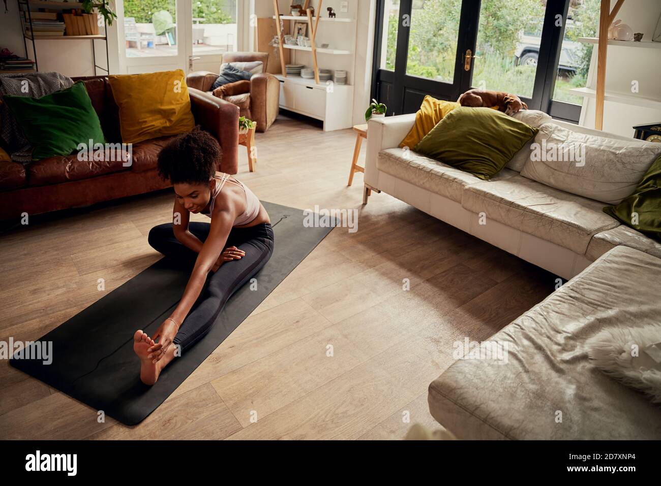 High angle view of young happy woman at home doing stretching exercise Stock Photo