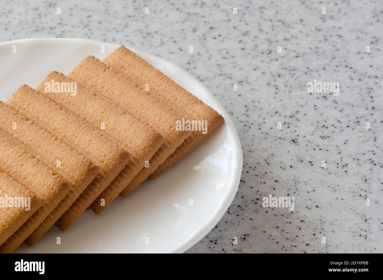 Rectangular shortbread cookies and chocolates in a white plate on a marble top. Stock Photo