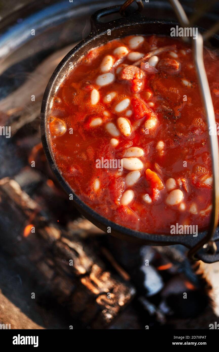 Spicy chorizo,bean,tomato and egg stew cooking over fire pit Stock