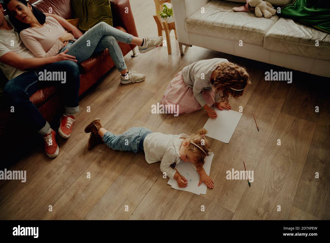 High angle view of two beautiful girls lying on floor creating artwork on paper at home Stock Photo