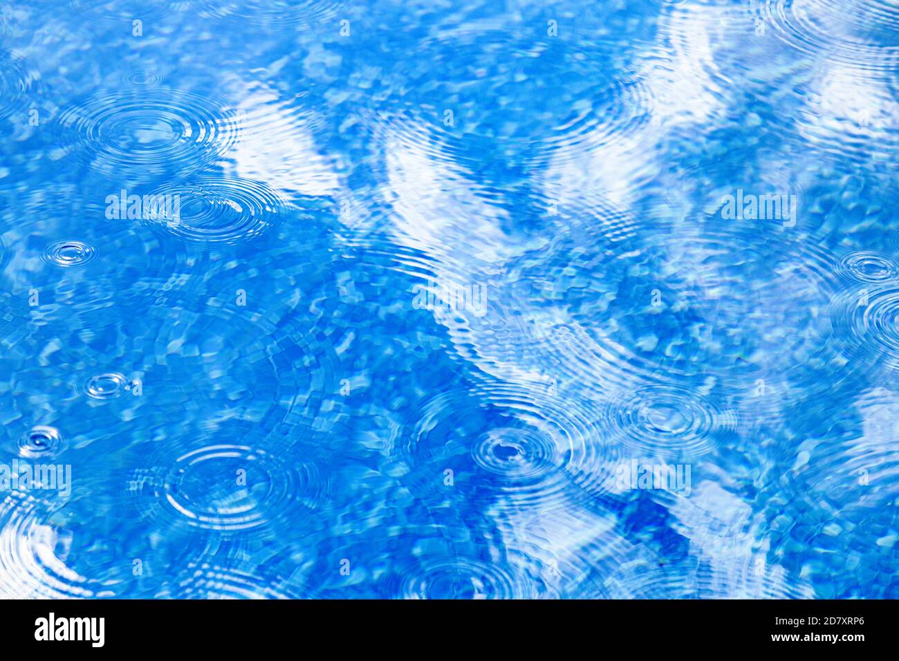 Raindrops on pool blue water surface. Blue water texture as background. Stains circles on the water from rain Stock Photo