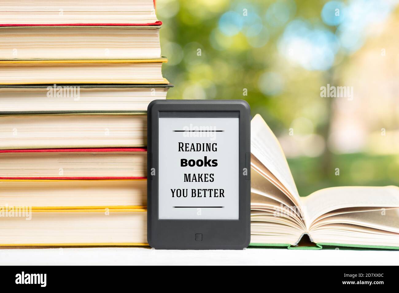 Reading and knowledge. Ebook reader and a stack of books. The park is