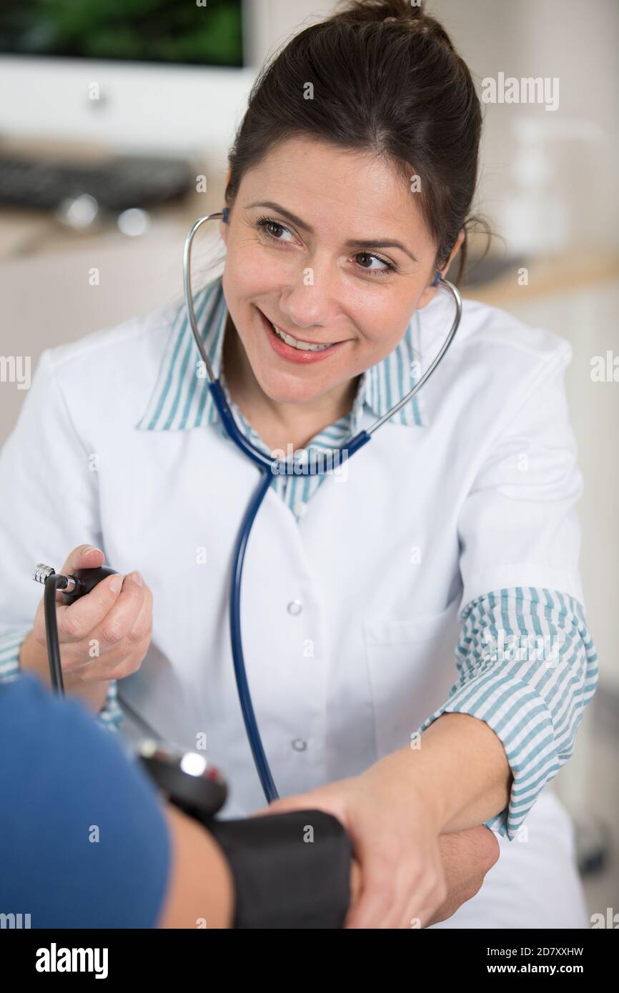caucasian young nurse girl taking blood pressure to a patient Stock Photo