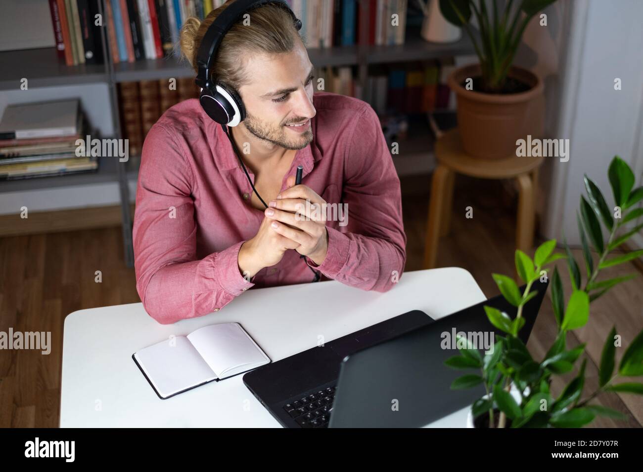 Handsome young caucasian man using computer working at home and talking with headphones feeling happy with smile showing teeth Stock Photo