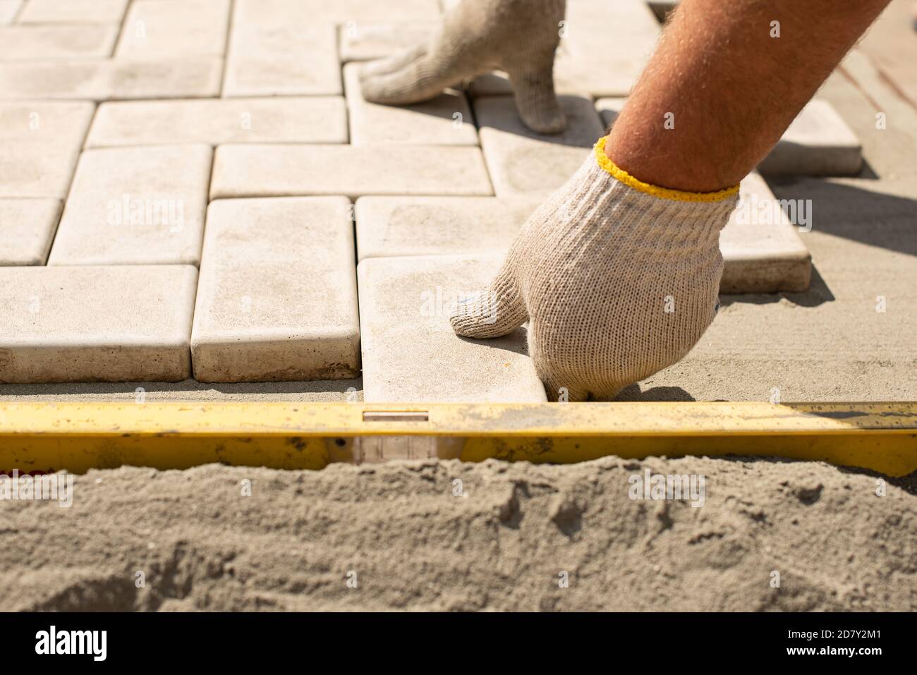 The master lays paving stones in layers. Garden brick pathway paving