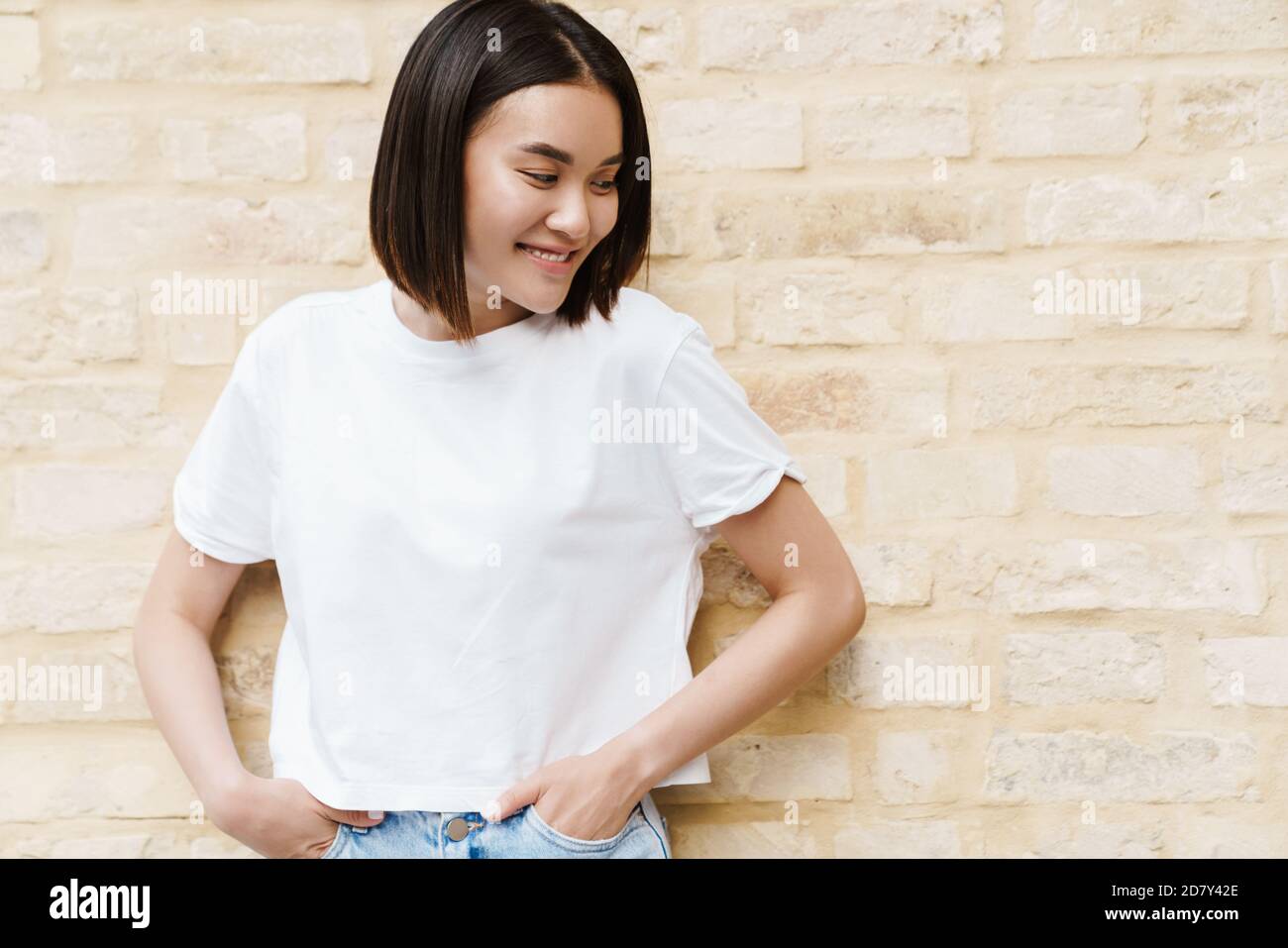 Picture of a happy young asian woman posing over wall outdoors Stock ...