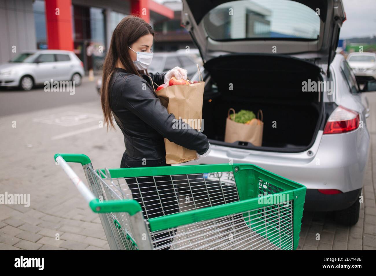 Young woman in protective mask and disposable gloves carries a craft ...