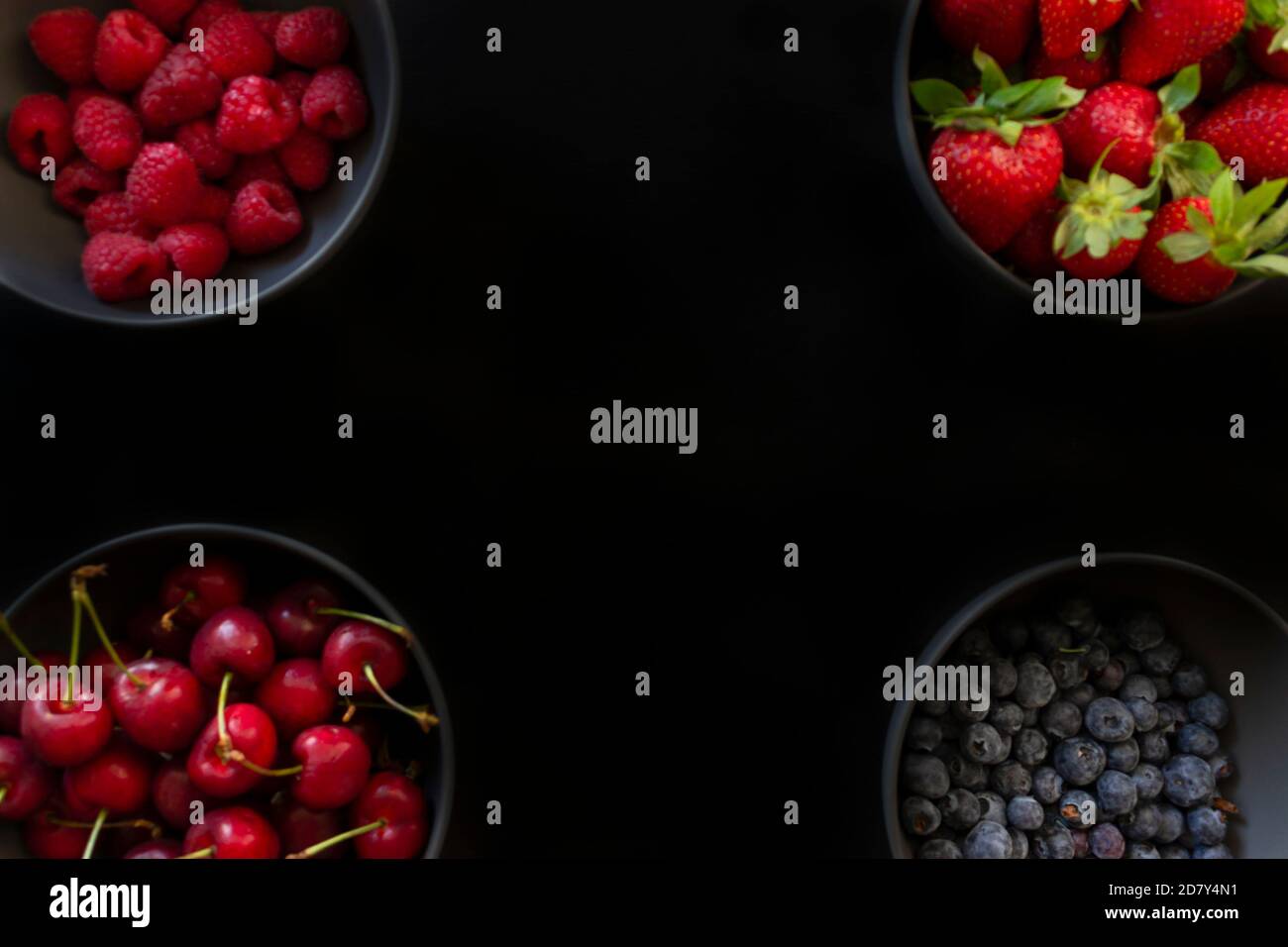 Berries and cherries in four bowls, creative food concept.Fresh