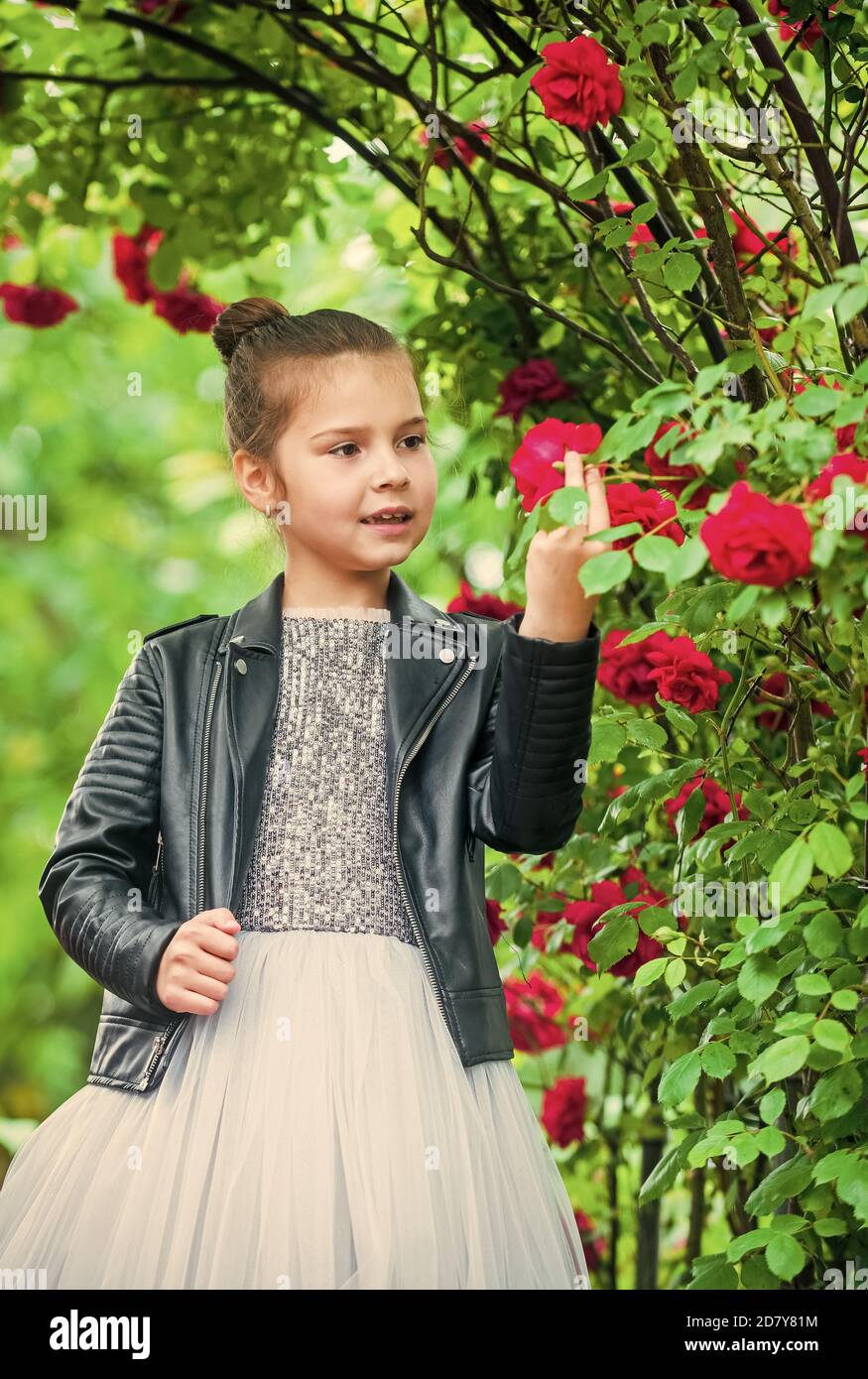 Trendy girl fancy dress and leather jacket in roses garden cool