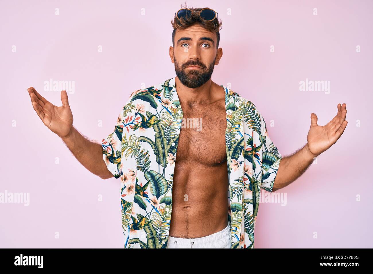Young hispanic man wearing casual summer clothes serious face thinking about question with hand on chin, thoughtful about confusing idea Stock Photo