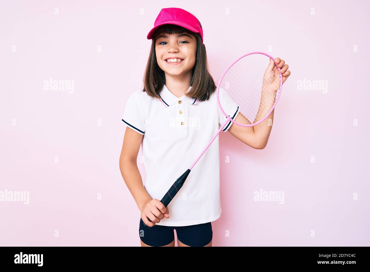 Young little girl with bang holding badminton racket smiling with a ...