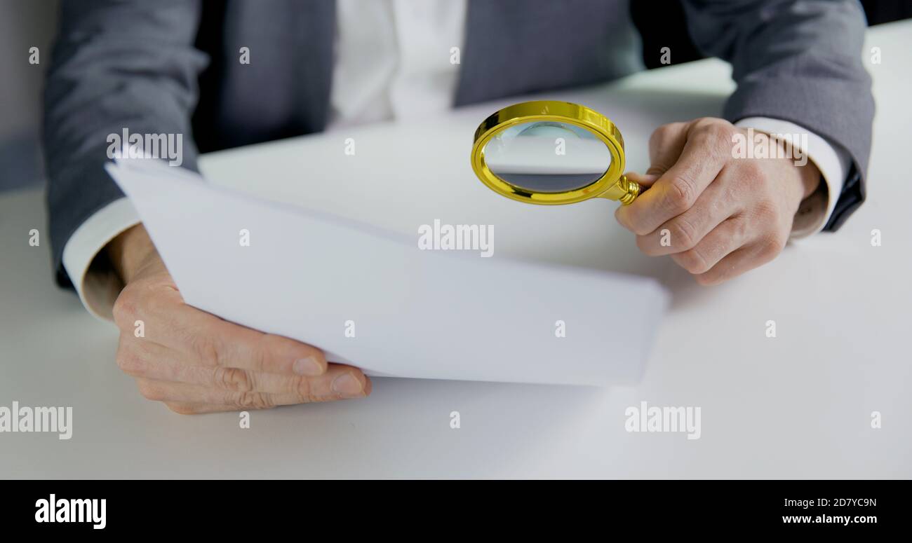 businessman or auditor inspecting document with magnifying glass in office. business financial audit or contract reading concept Stock Photo