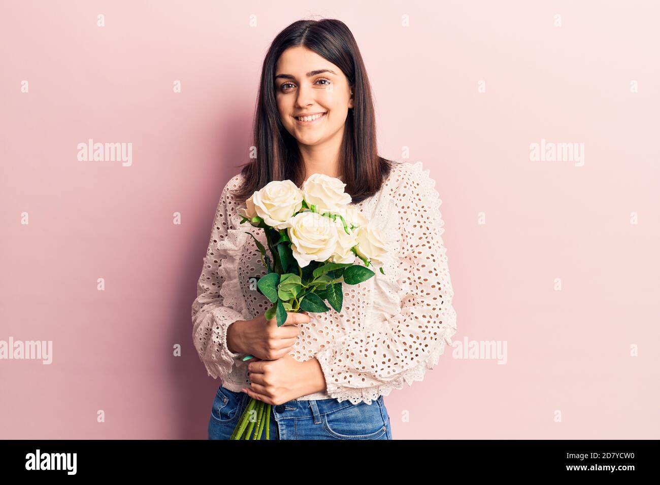 Young beautiful girl holding bouquet of flowers looking positive and ...