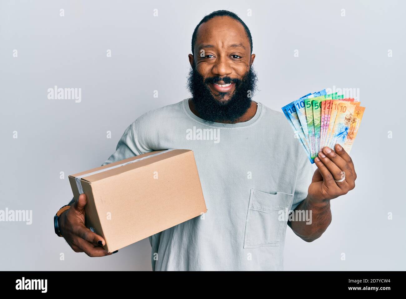 Young african american man holding delivery box and swiss franc ...