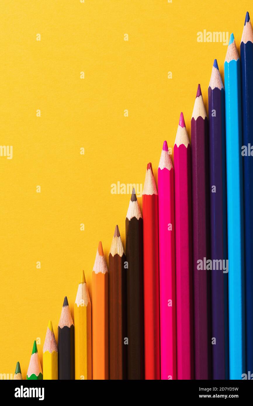 Colored pencils on yellow background, top view Stock Photo