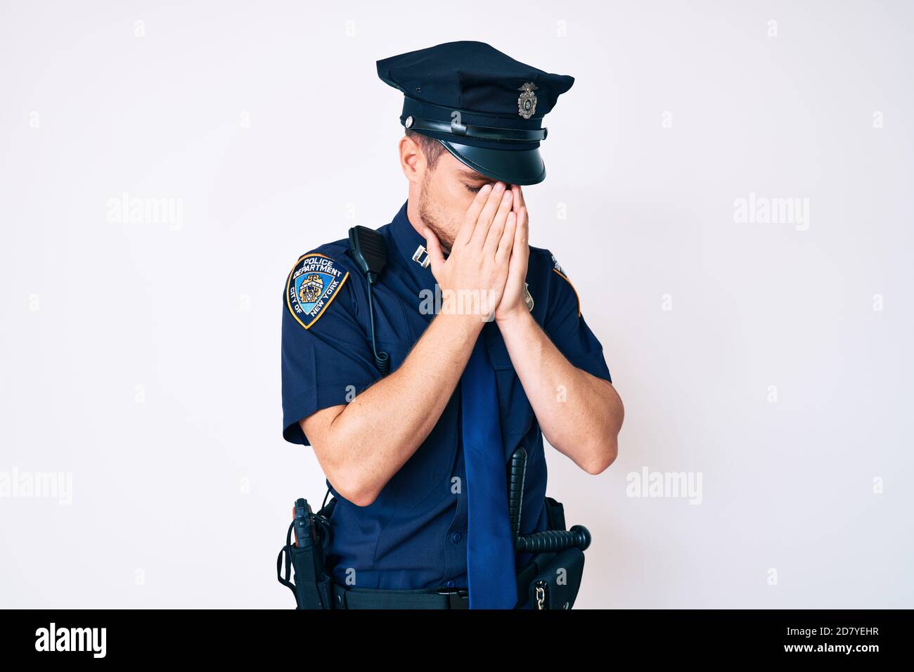 Young caucasian man wearing police uniform with sad expression covering face with hands while crying. depression concept. Stock Photo
