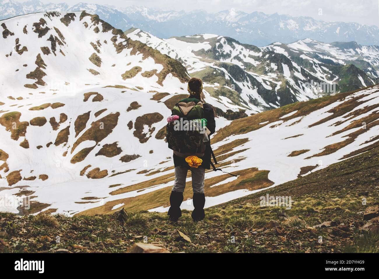 Rear view of female hiker with backpack standing on top of the mountain ...