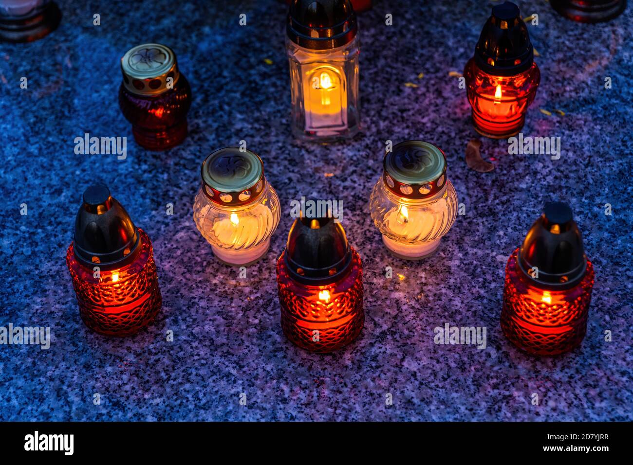 Candle lights on cemetery grave slab, All Saints Day holiday Stock Photo