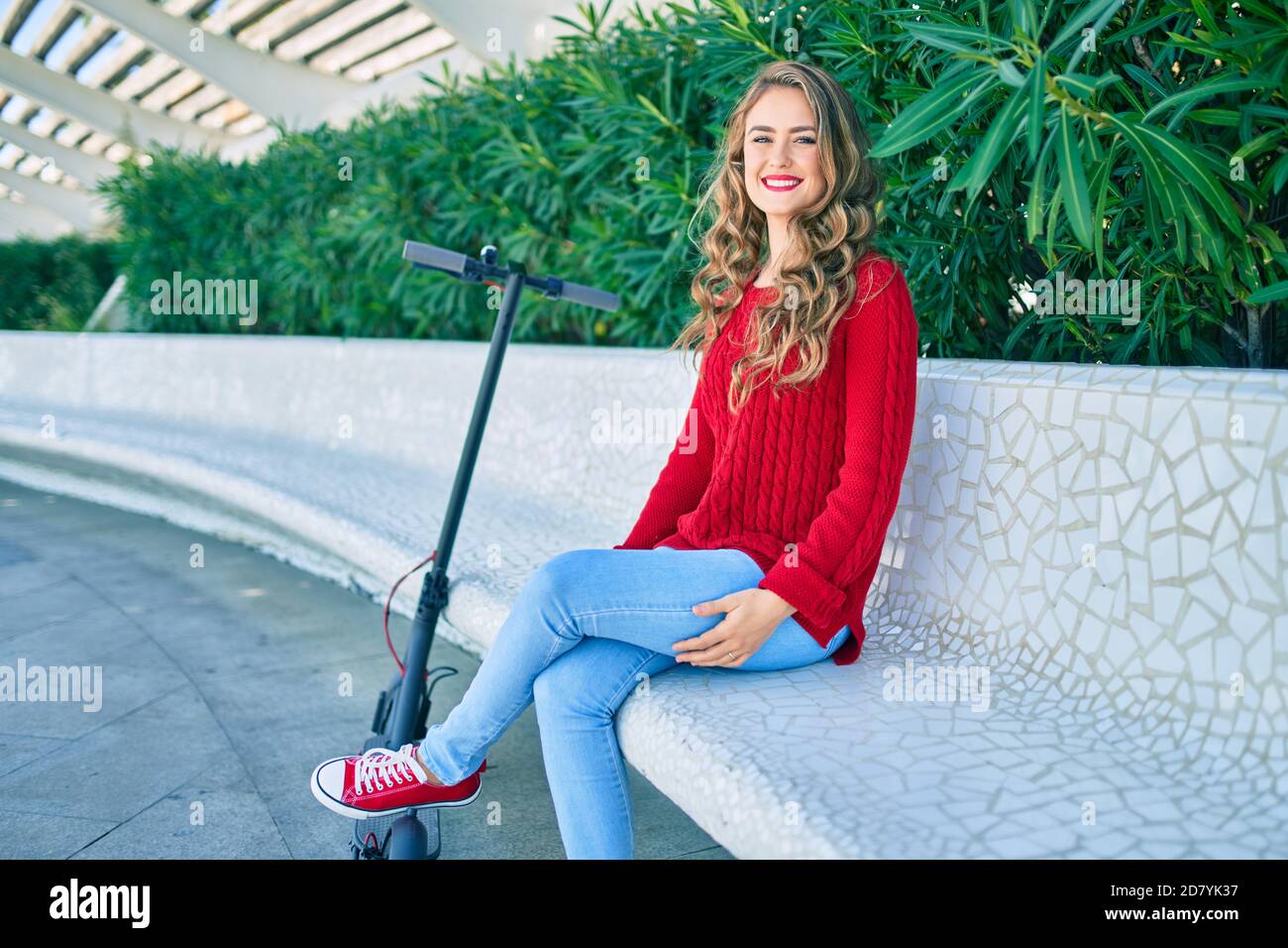 Young blonde girl smiling happy sitting on the bench at the park Stock ...