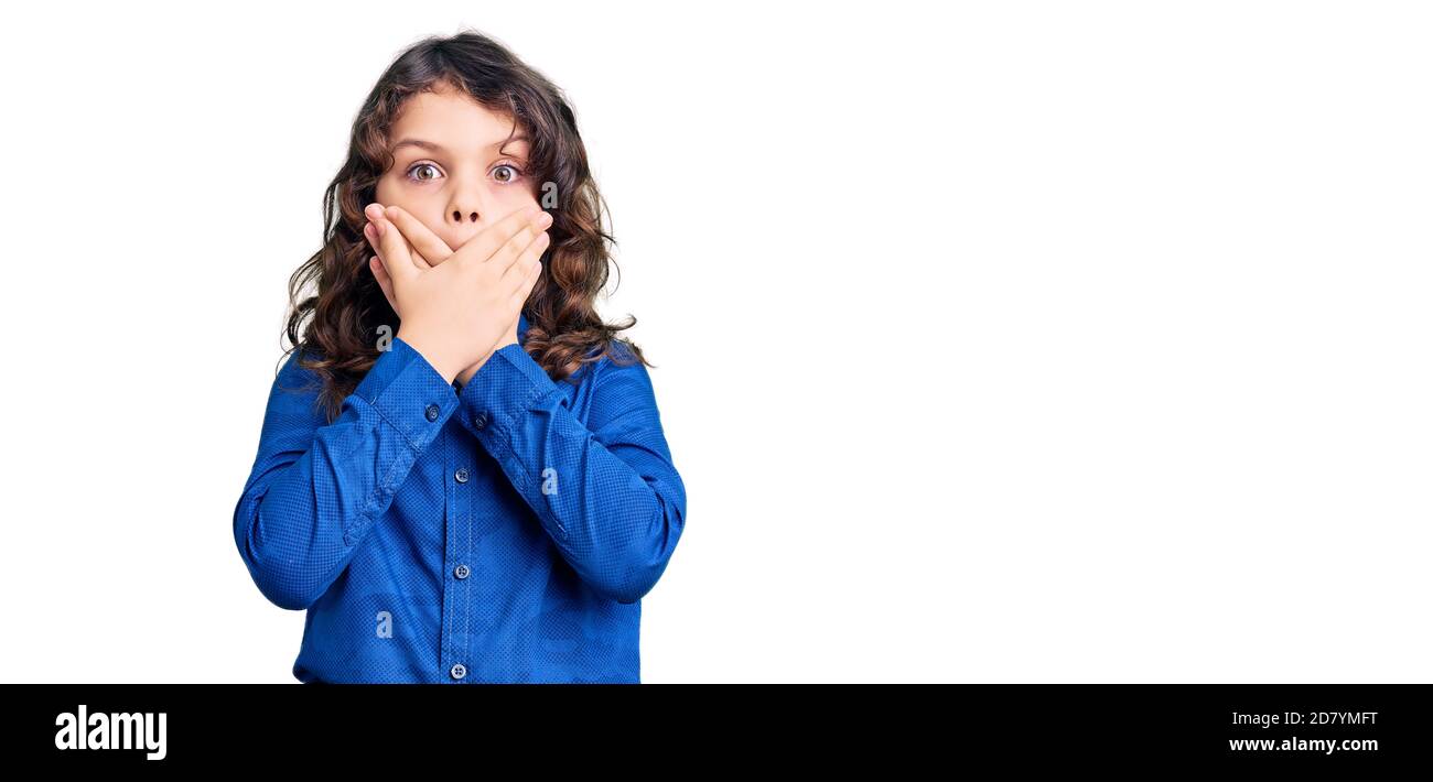 Cute child with long hair wearing casual clothes shocked covering mouth with hands for mistake. secret concept. Stock Photo