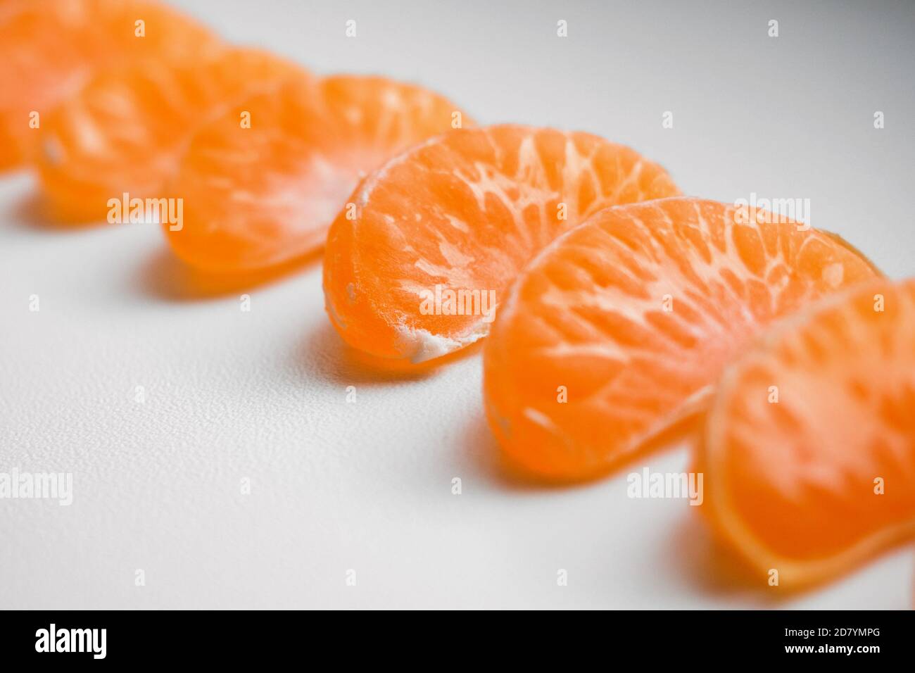 Slice sections of tangerine served on angle over the white background. Selective focus Stock Photo