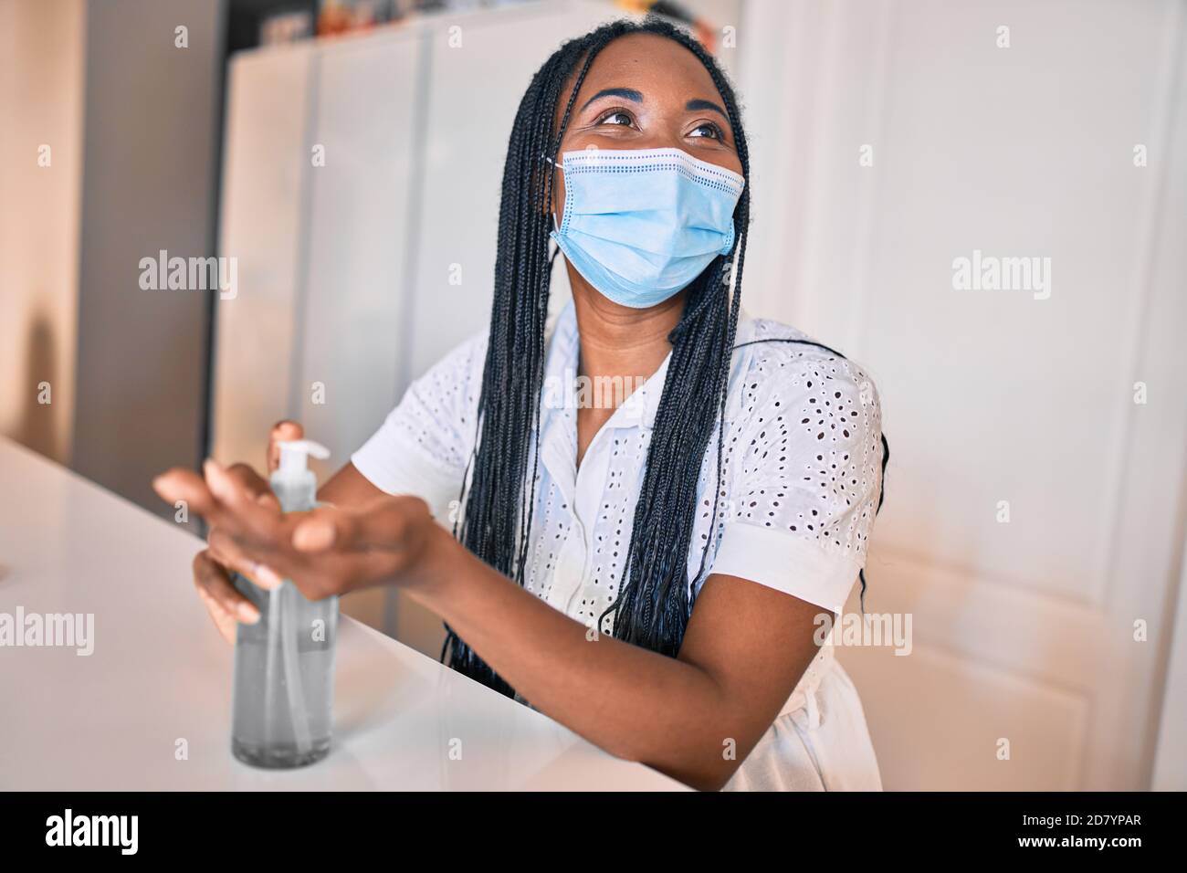Young african american woman wearing medical mask using sanitizer hand ...