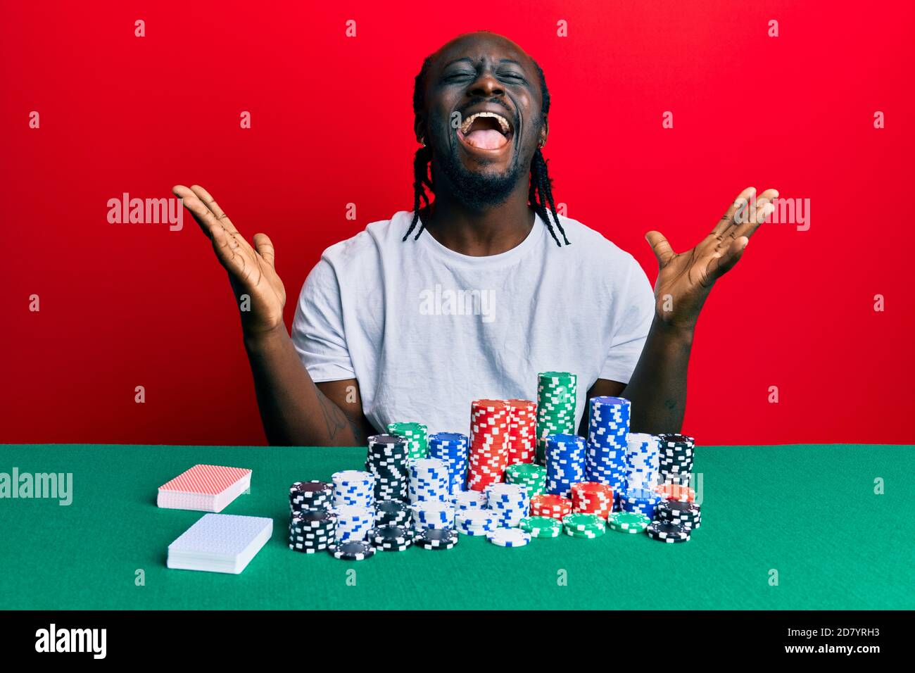 Handsome young black man sitting on the table with poker chips and