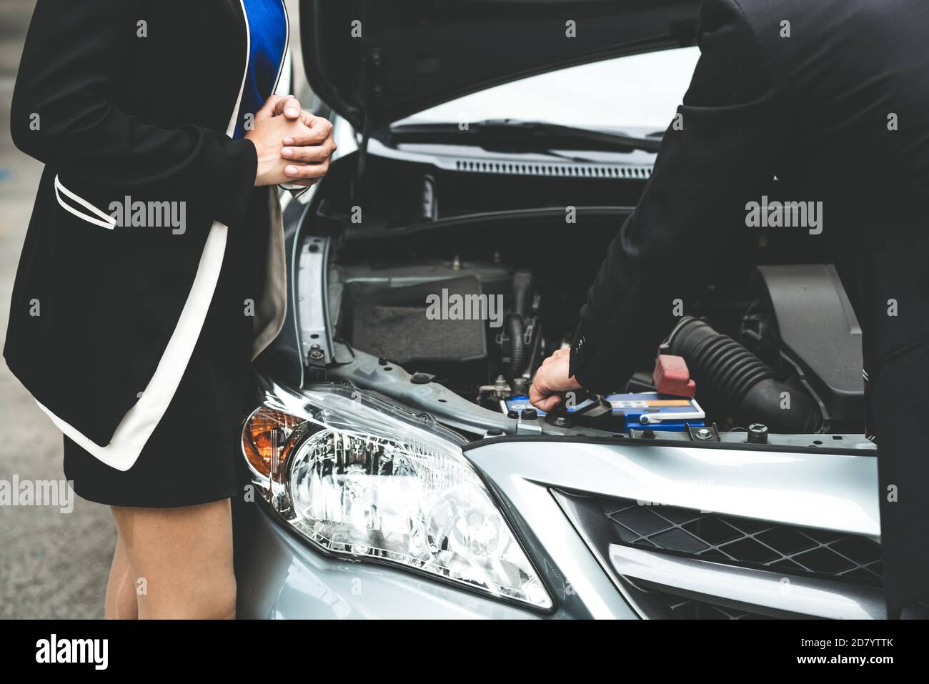 Man help woman fix the car problem. He pop up the car hood to repair
