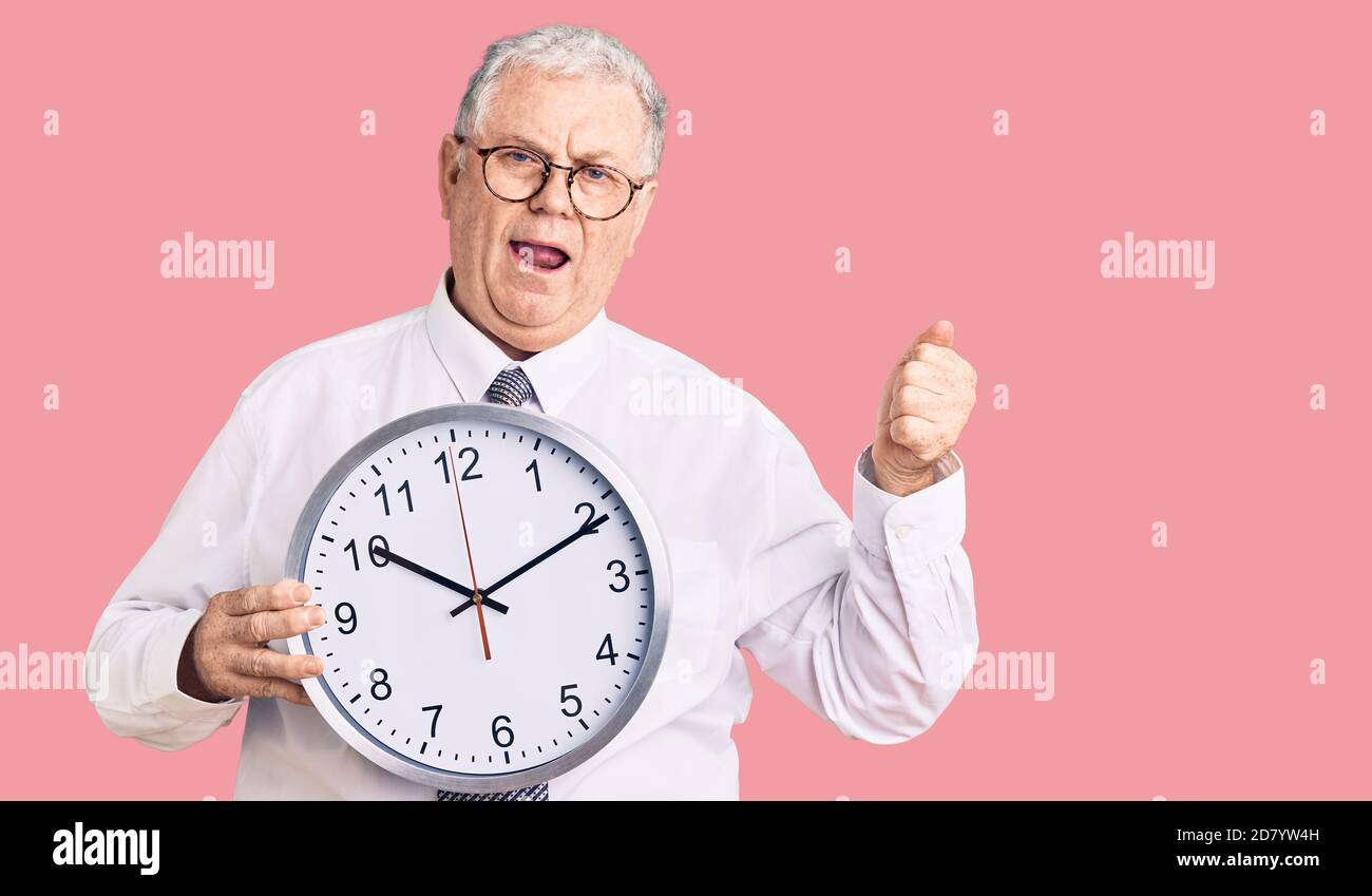 Senior grey-haired man wearing business clothes and holding clock ...