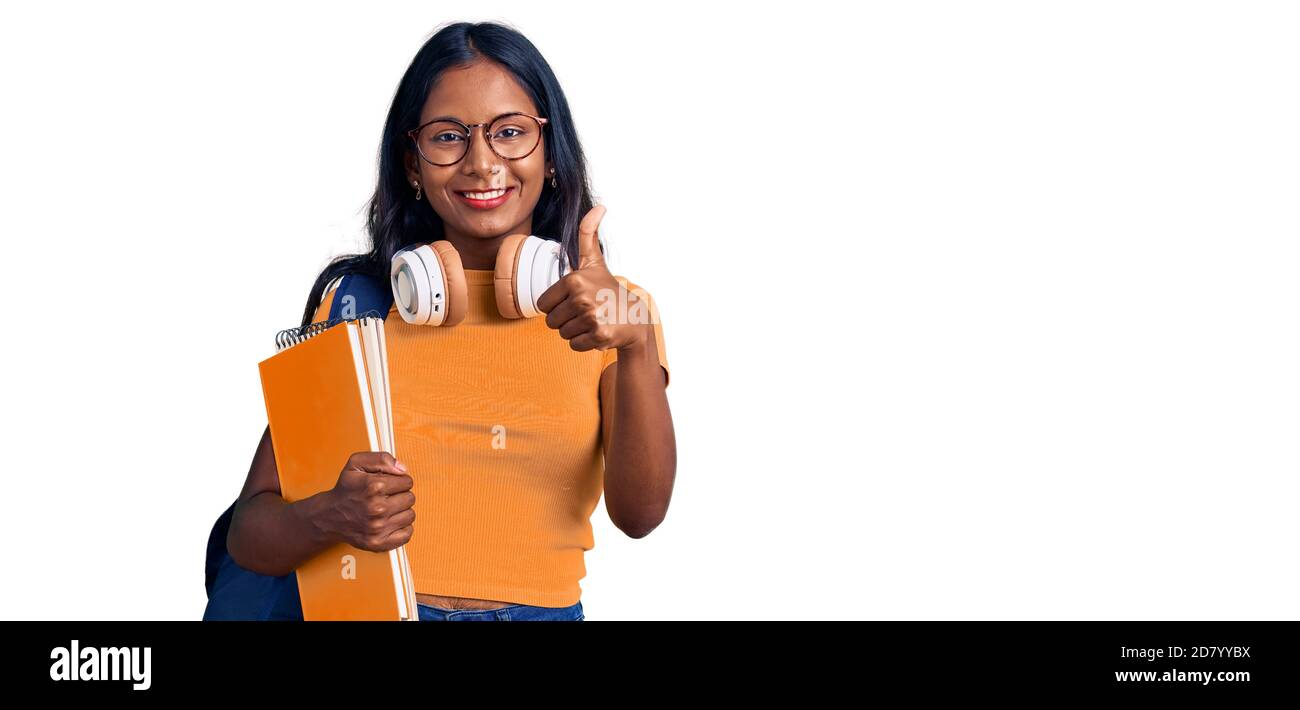 Young indian girl holding student backpack and books smiling happy and ...