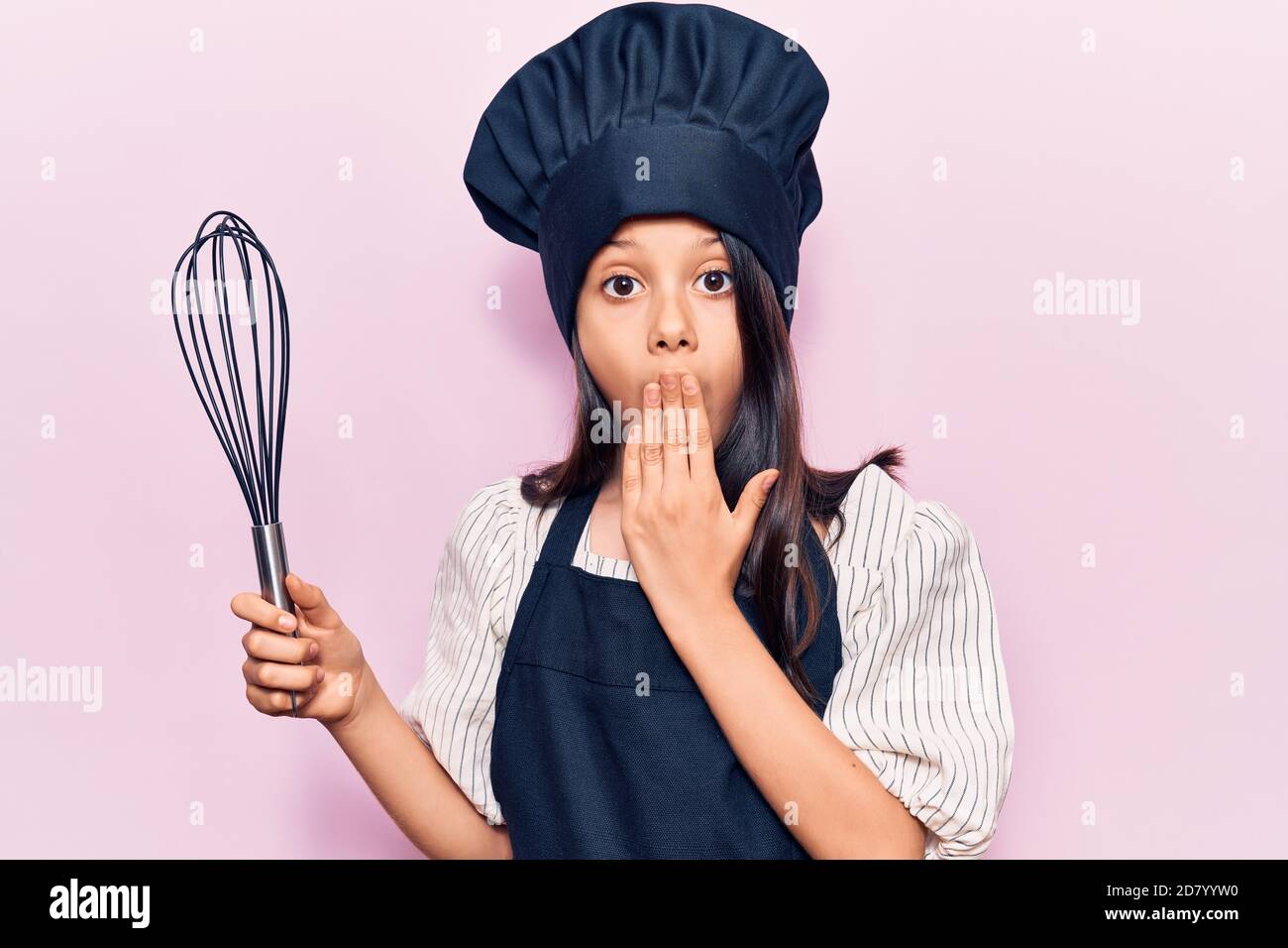 Beautiful child girl wearing cooker uniform holding whisk covering