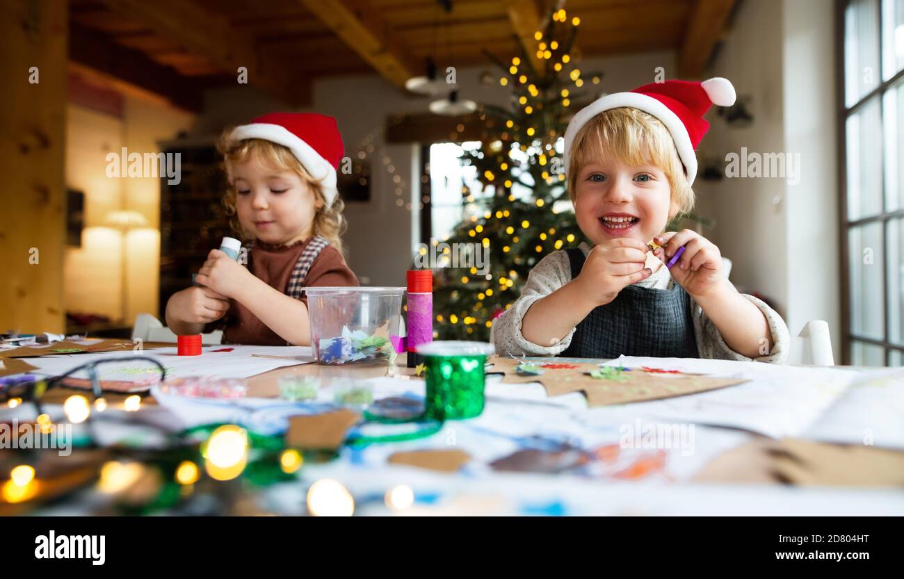 Portrait of small girl and boy indoors at home at Christmas, doing art and craft. Stock Photo