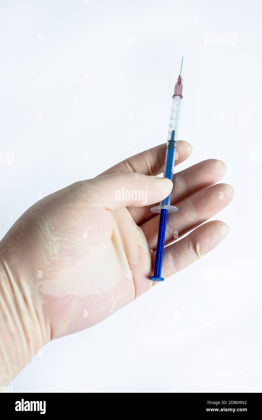 In the hand of rubber gloves hold a syringe Stock Photo