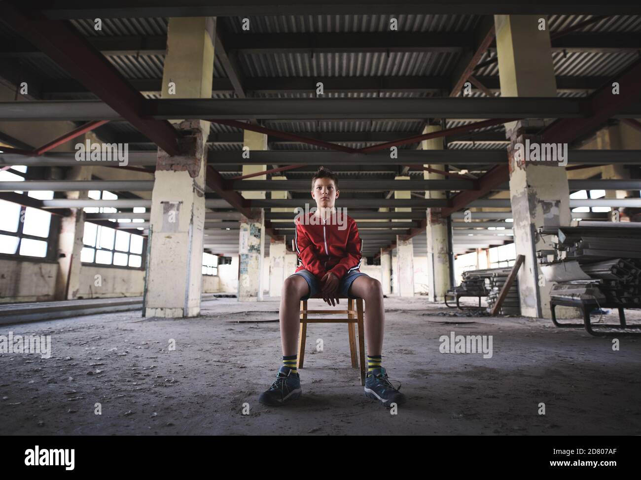 Sad and disappointed teenagers boy sitting indoors in abandoned building. Stock Photo