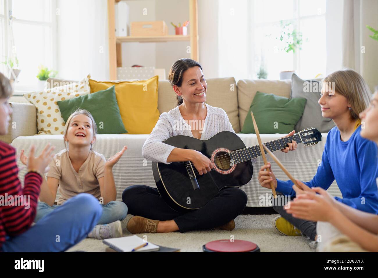 Group of homeschooling children with teacher having music lesson indoors, coronavirus concept. Stock Photo