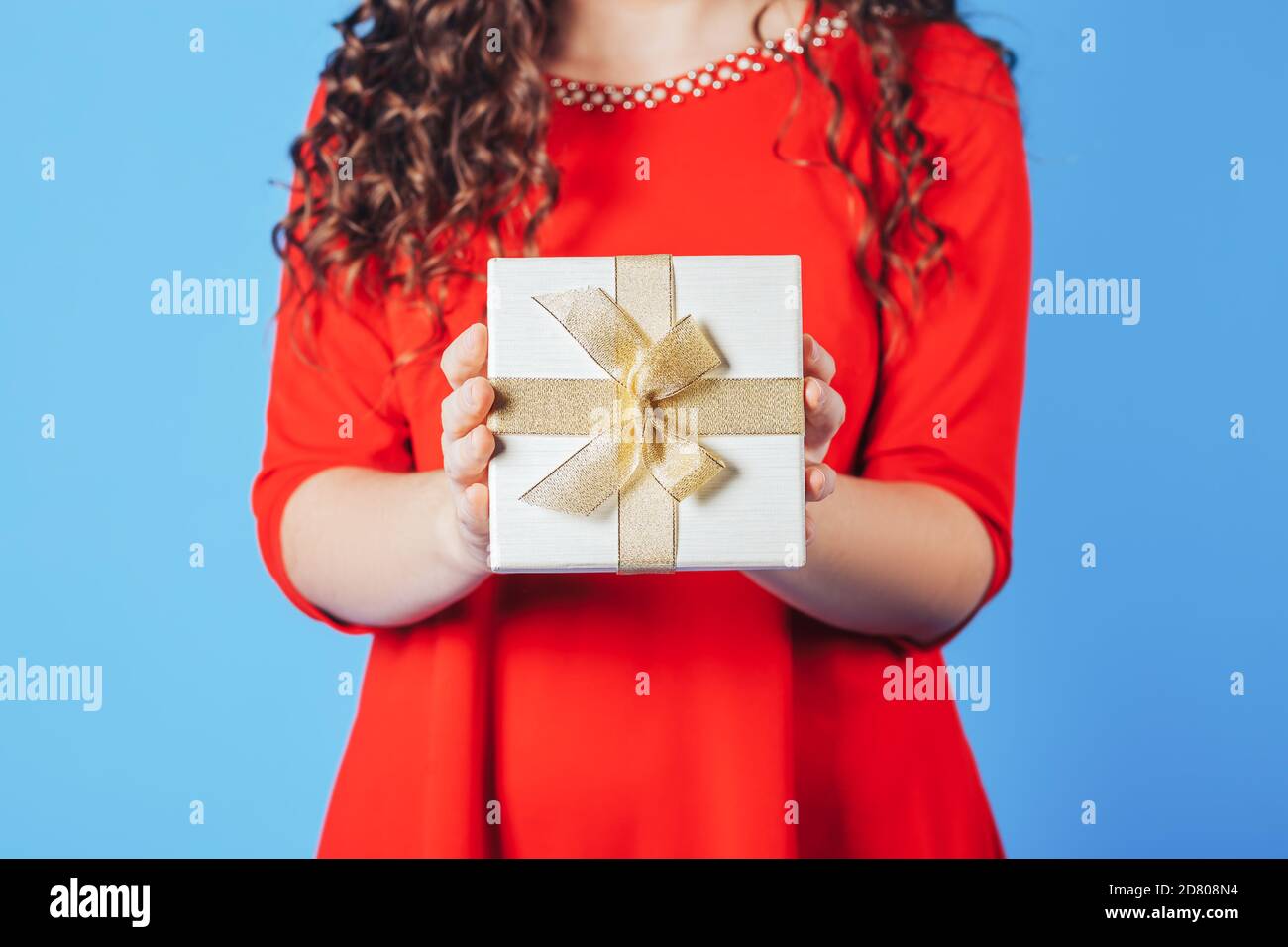 Beautiful woman in red dress on a blue background holding box with a ...
