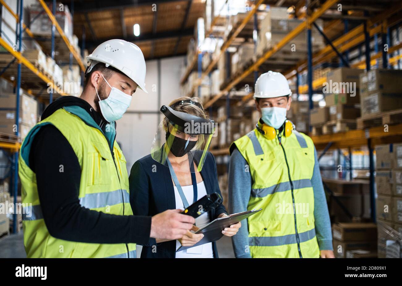 Group of workers with manager working indoors in warehouse, coronavirus concept. Stock Photo
