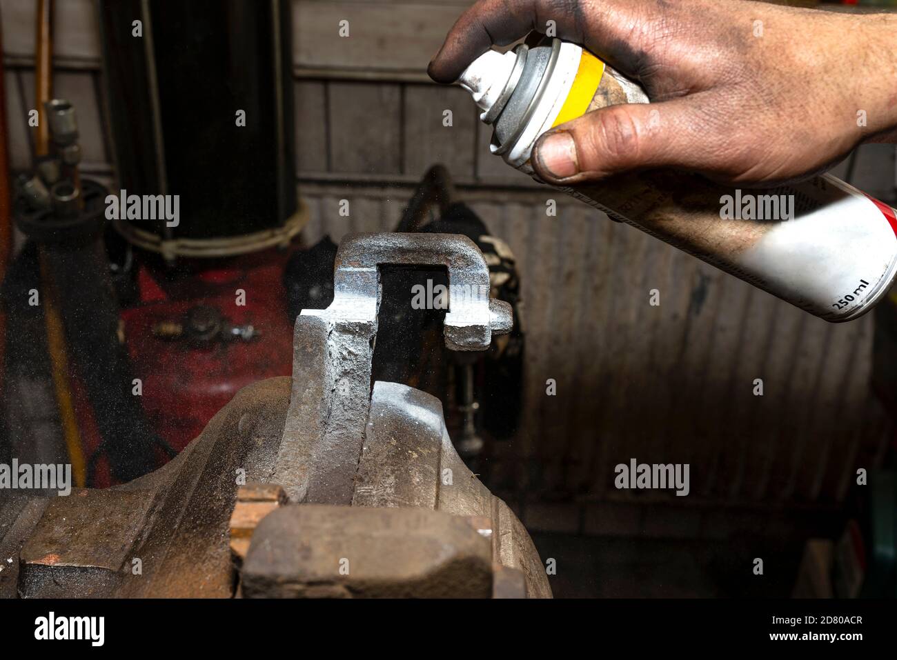 The mechanic lubricates the brake caliper in a table vise with ceramic ...