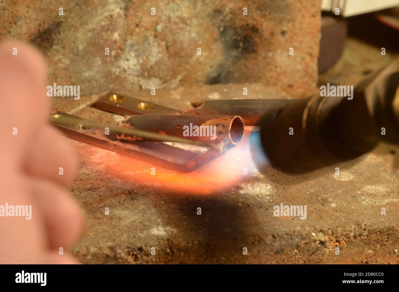 A brass item is being silver soldered with a gas torch. Stock Photo