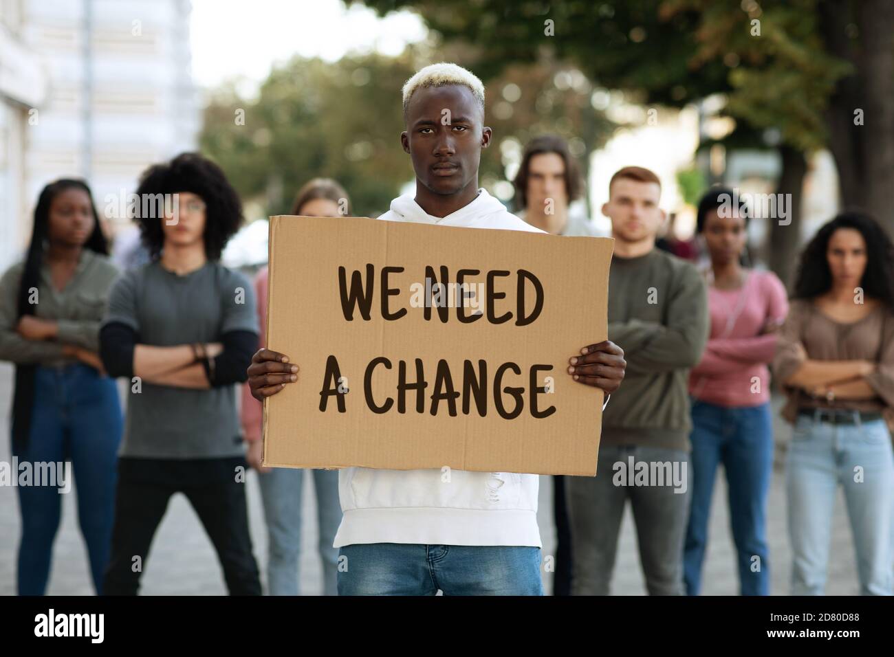 Black man with we need a change placard leading group Stock Photo