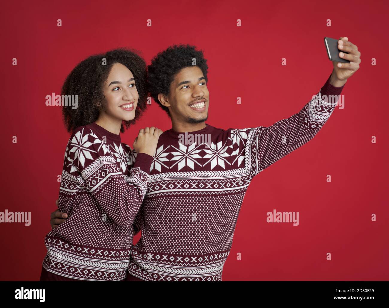 Guy and lady in identical New Year outfits happily pose for selfie Stock Photo