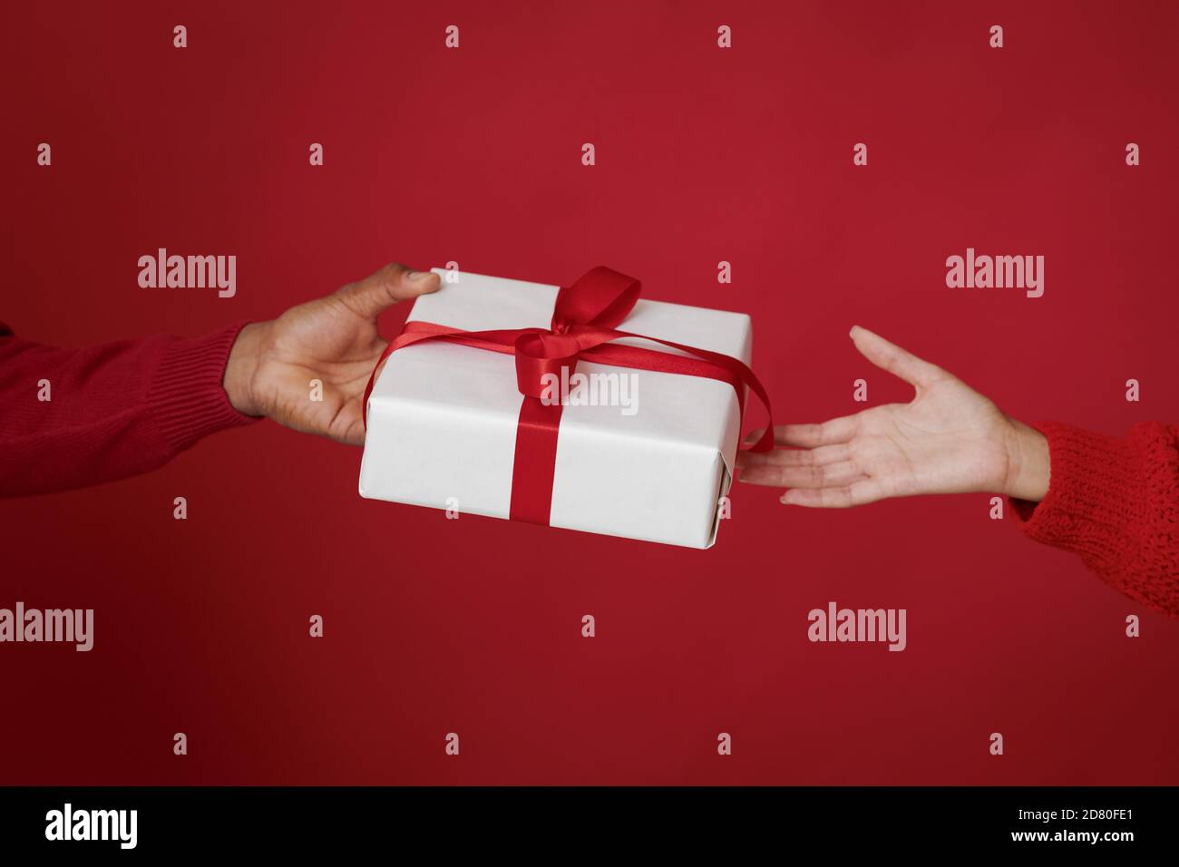Happy New Year and Merry Christmas. African american husband giving box with gift to wife in sweater Stock Photo