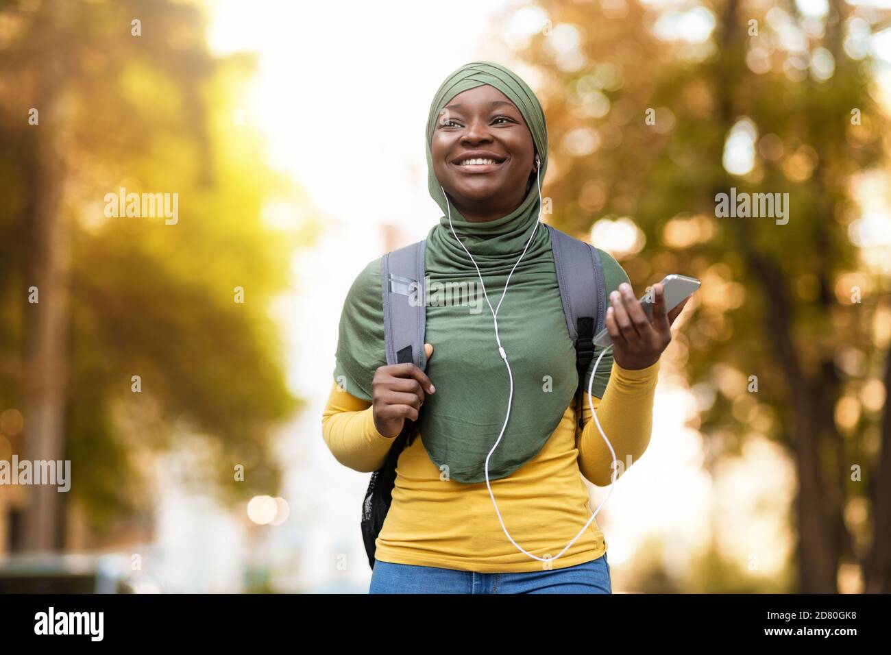 Black muslim woman in hijab listening music with smartphone and ...