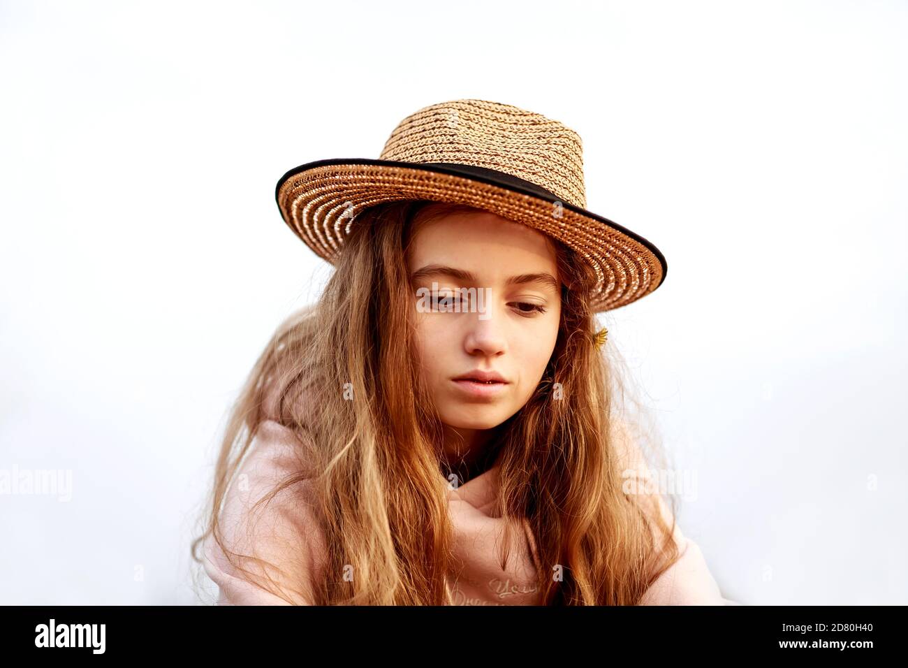 Portrait of a beautiful teenage girl in a straw hat against the sky looking down. Stock Photo