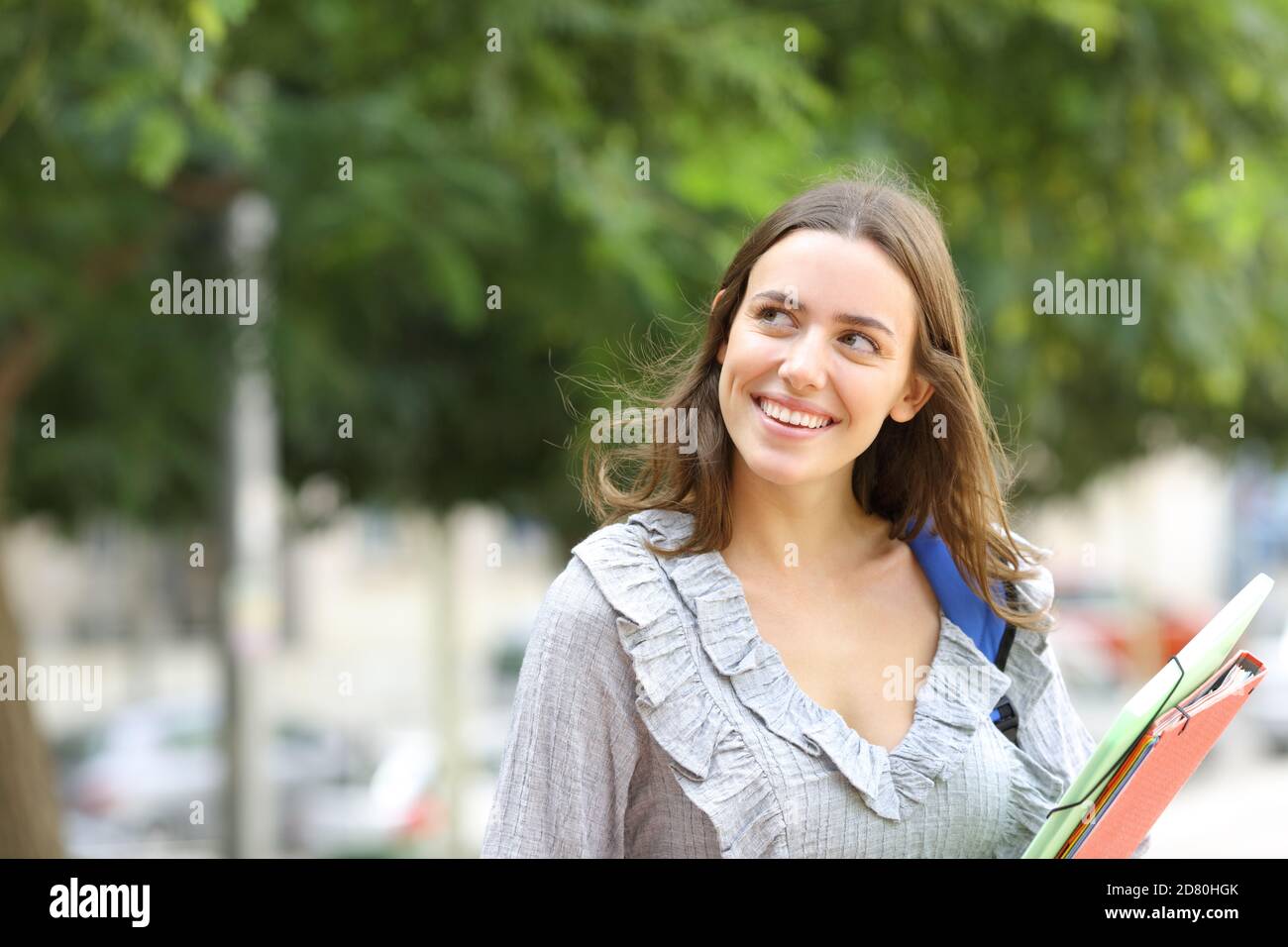 Happy student thinking looking at side standing in the street Stock Photo