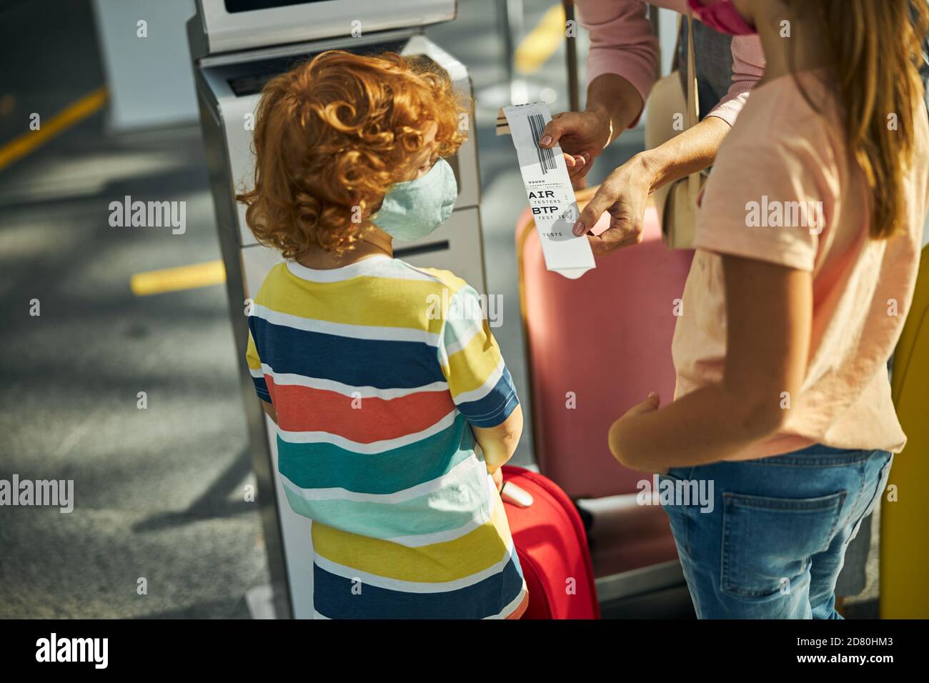 Woman showing children a tag from a bag drop counter Stock Photo