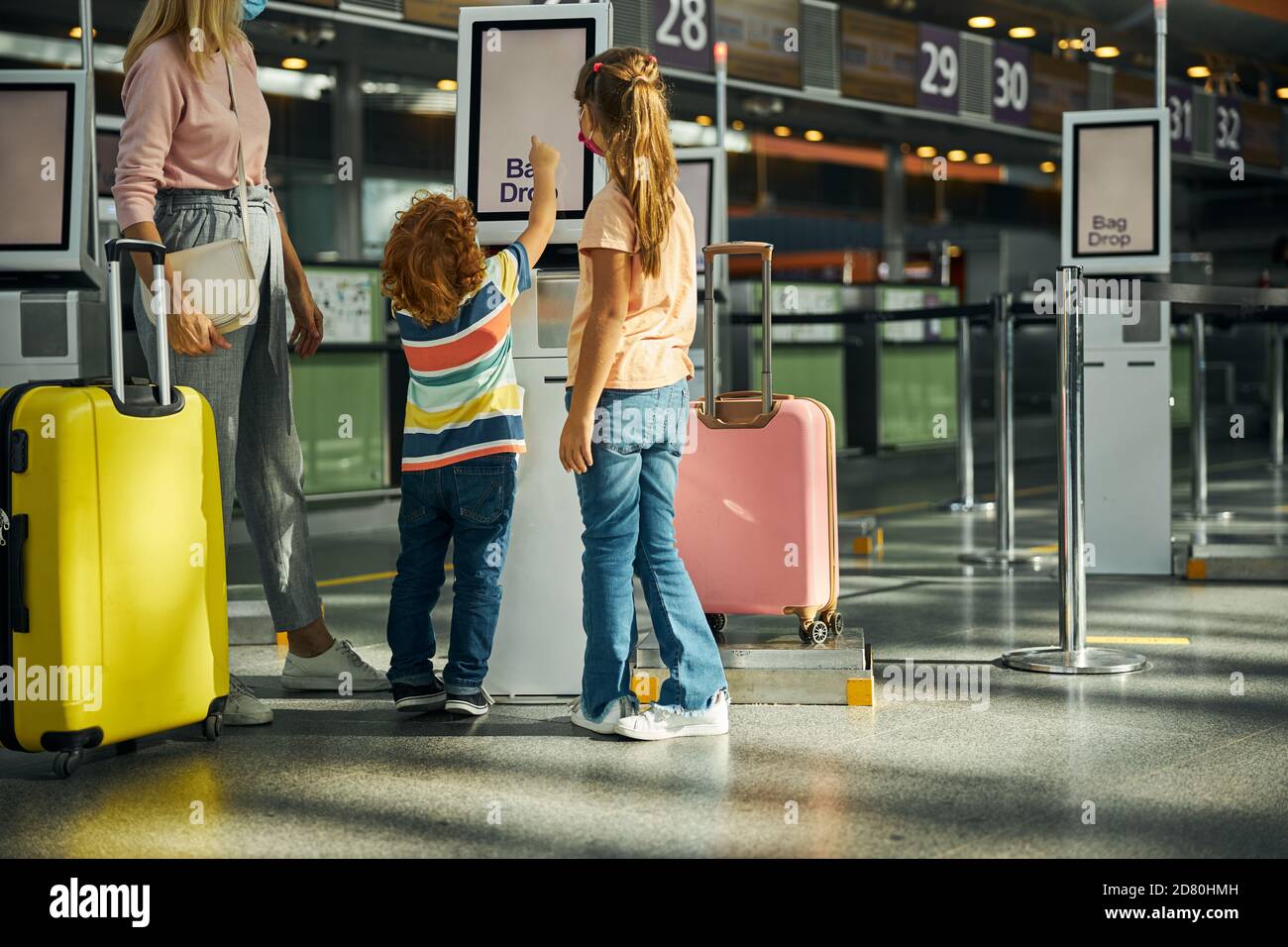Curious boy touching a screen of a bag drop kiosk Stock Photo